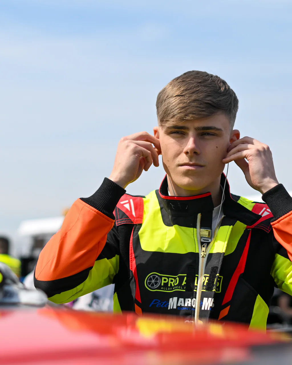 Torq race driver preparing for a session beside his helmet in the paddock.